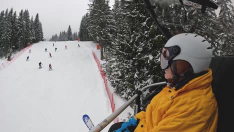 Skier-On-Chair-Lift-Across-Snow-Covered-Mountain-Below