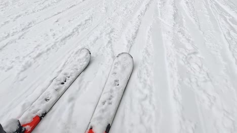 POV-Aufnahme-Eines-Skifahrers,-Der-Einen-Schneebedeckten-Hang-Hinunterfährt-Und-Auf-Die-Skier-Blickt-1