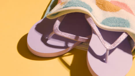 Summer-Holiday-Vacation-Concept-Of-Flip-Flops-Sandals-Beach-Towel-On-Yellow-Background-1