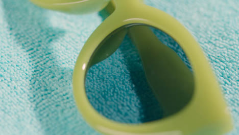 Close-Up-Summer-Holiday-Concept-Of-Green-Sunglasses-On-Beach-Towel