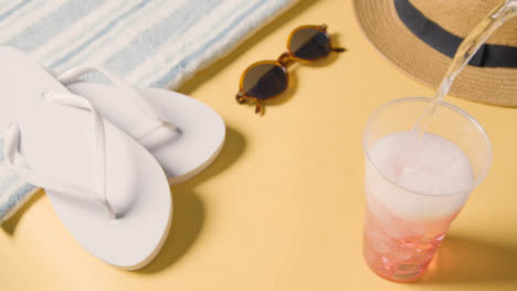 Sommerferienkonzept-Sonnenhut-Sonnenbrille-Strandtuch-Flip-Flops-Kaltes-Getränk