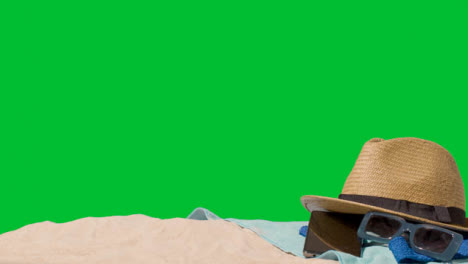 Summer-Holiday-Concept-Of-Sunglasses-Sun-Hat-Mobile-Phone-Beach-Towel-On-Sand-Against-Green-Screen