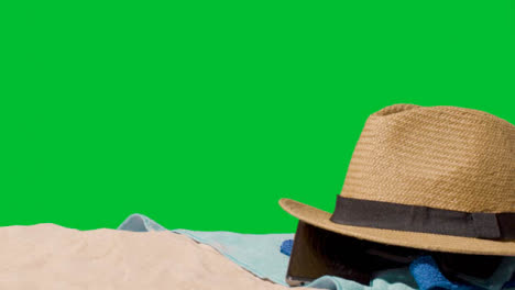 Sommerferienkonzept-Der-Sonnenbrille-Sonnenhut-Handy-Strandtuch-Auf-Sand-Gegen-Grünen-Bildschirm-1
