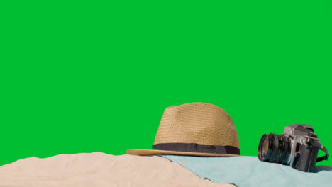 Summer-Holiday-Concept-Of-Sunglasses-Sun-Hat-Camera-Beach-Towel-On-Sand-Against-Green-Screen-2