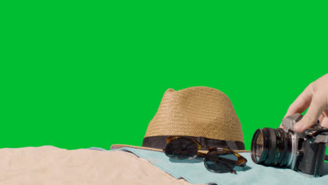 Summer-Holiday-Concept-Of-Sunglasses-Sun-Hat-Camera-Beach-Towel-On-Sand-Against-Green-Screen-4