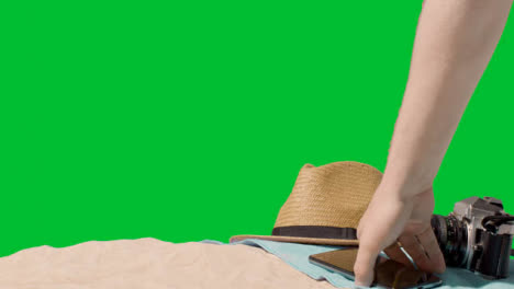 Summer-Holiday-Concept-Of-Camera-Sun-Hat-Mobile-Phone-Beach-Towel-On-Sand-Against-Green-Screen-3
