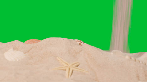 Summer-Holiday-Concept-Pouring-Sand-Onto-Beach-With-Shells-Starfish-Against-Green-Screen