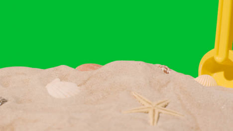 Sommerferienkonzept-Mit-Kinderplastikspaten-Am-Sandstrand-Gegen-Grünen-Bildschirm