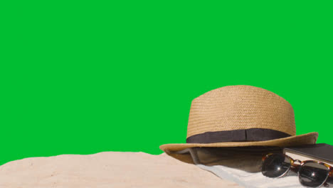 Sommerferienkonzept-Des-Sonnenbrillenbuch-Sonnenhut-Strandtuchs-Auf-Sand-Gegen-Grünen-Bildschirm