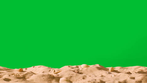Summer-Holiday-Concept-With-Shells-Starfish-On-Sandy-Beach-In-Foreground-Against-Green-Screen-3