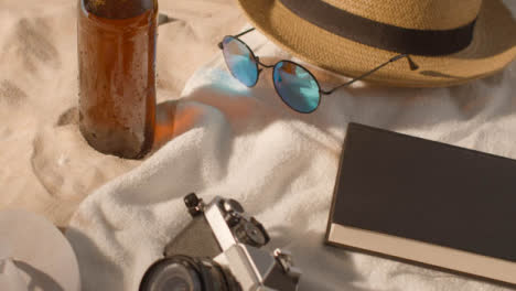Sommerferienkonzept-Der-Bierflasche-Sonnenbrille-Strandtuch-Buch-Sonnenhut-Kamera-Auf-Sand-1