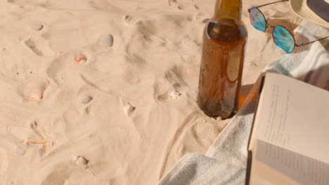 Summer-Holiday-Concept-Of-Beer-Bottle-Sunglasses-Beach-Sun-Hat-Book-On-Sand