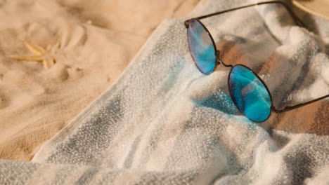 Sommerferienkonzept-Von-Sonnenbrillen-Strandtuchschalen-Auf-Sandhintergrund