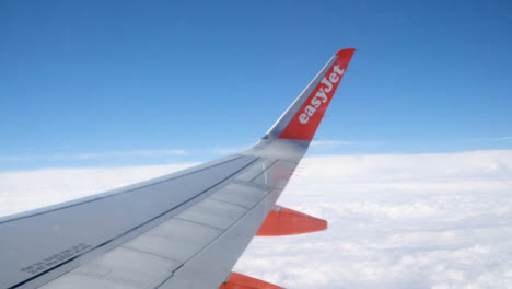 View-From-Plane-Window-Of-Blue-Sky-And-Clouds-On-Flight-To-Summer-Holiday-Vacation