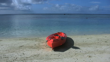 Aitutaki-Red-Kayak-Sits-On-A-Beach-By-A-Lagoon