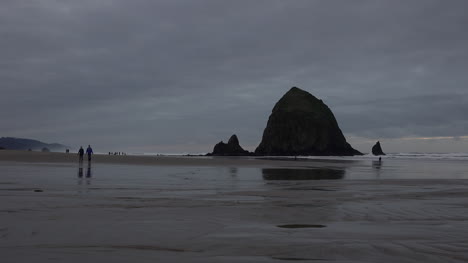 Oregon-Haystack-Rock-With-Walking-Tourists-In-Evening