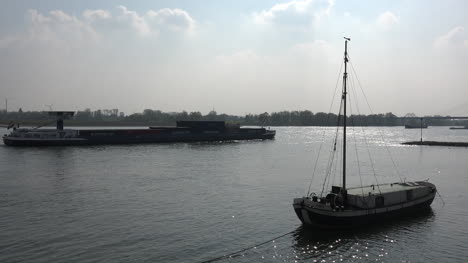 Germany-Barge-Passes-Backlit-Sailboat-On-Rhine