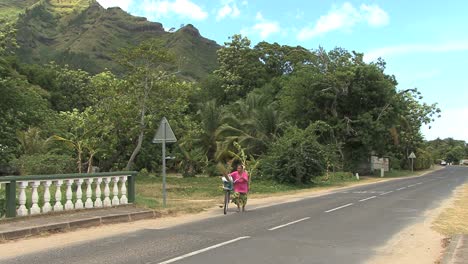 Moorea-woman-pushes-bike-on-road