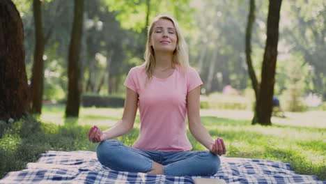 Happy-Woman-Practices-Yoga-And-Meditates-In-Lotus-Pose-Sitting-On-The-Grass-Outdoors