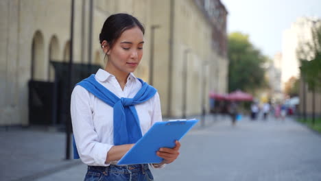 Woman-Working-On-The-Street-Reading-Documents-On-A-Clipboard