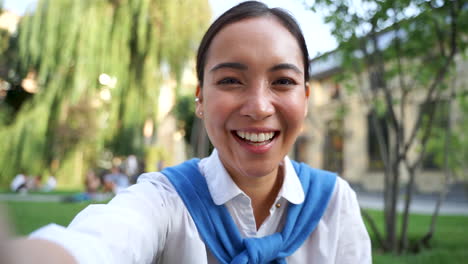 Cheerful-Woman-Having-A-Video-Call,-Waving-Hand-At-Camera-And-Smiling-Outdoors