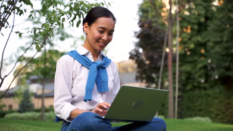 Cheerful-Woman-Using-Her-Laptop-Outdoors