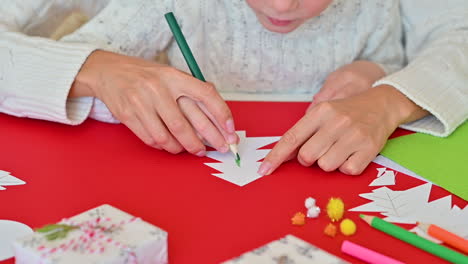 Kind-Malt-Einen-Papierausschnitt-weihnachtsbaum-Mit-Einem-Bleistift