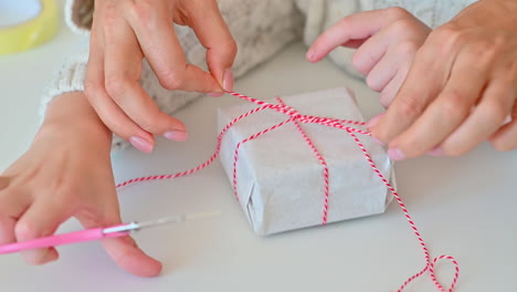 Hands-Tie-The-Bow-Of-A-Gift-Box-With-Wrapping