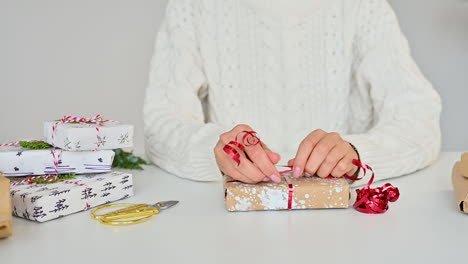 Weibliche-Hände-Binden-Den-Bogen-Einer-Geschenkbox-Mit-Verpackung,-Die-Mit-Bemaltem-Schnee-Verziert-Ist