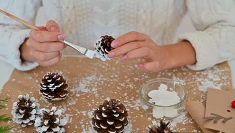 Woman-Hands-Decorate-Pine-Cones-With-White-Paint-For-Christmas