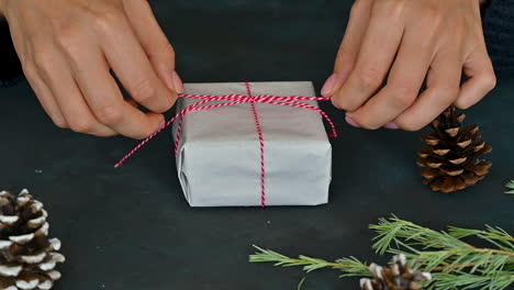 Woman-Hands-Tie-The-Red-Rope-Of-A-Gift-Box-With-White-Wrapping