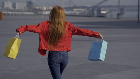 Young-Pretty-Red-Haired-Excited-Woman-With-Shopping-Bags-Walking-Outdoors