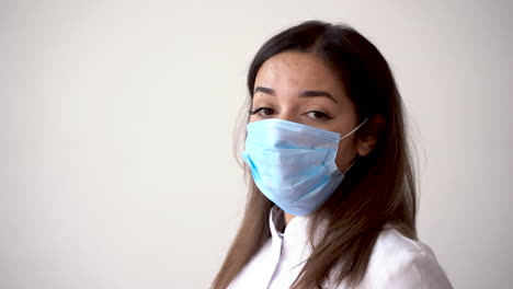 Portrait-Of-Female-Doctor-Putting-On-Medical-Mask-And-Making-The-Ok-Gesture