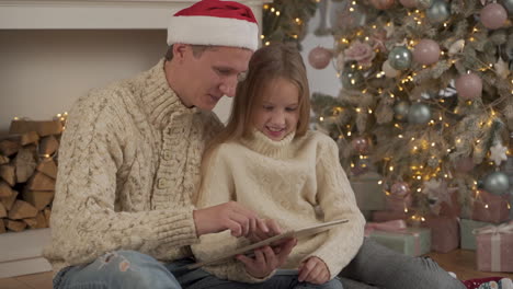 Familia-Feliz-Usando-Una-Tableta-En-Navidad-Con-Un-Sombrero-De-Santa
