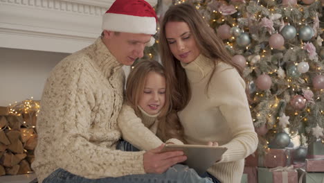 Familia-Feliz-Jugando-Con-Una-Tableta-En-Navidad-Usando-Un-Sombrero-De-Santa-1