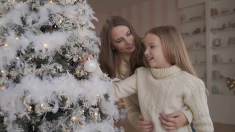Mother-And-Daughter-Decorate-Christmas-Tree-With-White-Garlands-And-Ornaments