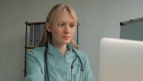 Portrait-Of-Young-Pretty-Blonde-Female-Nurse-Care-Taker-Using-A-Computer