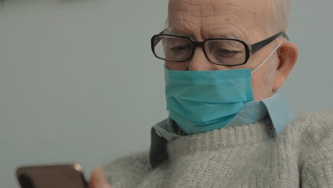 Portrait-Of-Elderly-Man-With-Face-Mask-Using-A-Smartphone