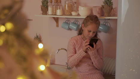Kleines-Mädchen-Benutzt-Ihr-Telefon,-Um-Frohe-Weihnachtsbotschaften-Zu-Hause-Zu-Senden