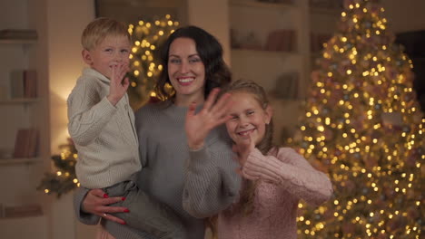 Frau,-Kleiner-Sohn-Und-Tochter,-Die-Zur-Kamera-Schauen-Und-An-Weihnachten-Mit-Der-Hand-Winken