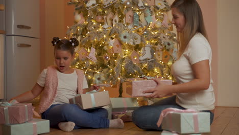 Little-Girl-And-Woman-Exchange-Gifts-By-The-Christmas-Tree
