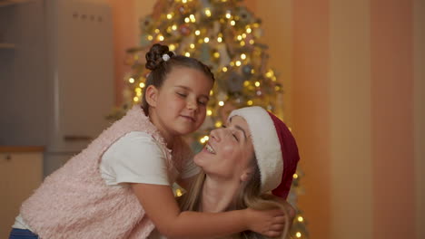 Little-Girl-Puts-Santa-Hat-On-Her-Mother-And-Kisses-Her
