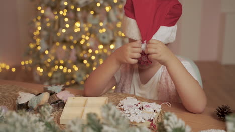 Little-Girl-Decorates-Her-Santa-Hat-With-Christmas-Decorations