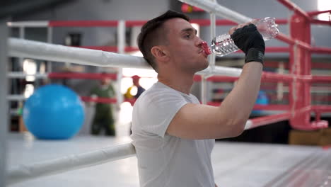 Strong-Athlete-Man-Takes-A-Break-And-Drinks-Water-In-The-Gym