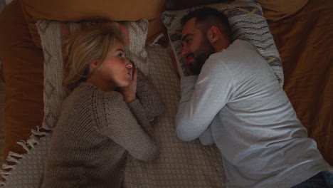Lovely-Couple-Lying-In-Bed-Looking-Each-Other,-Having-A-Romantic-Conversation-Face-To-Face-On-A-Winter-Day