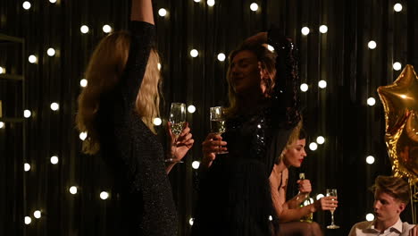Zwei-Junge-Hübsche-Frauen-Tanzen-Mit-Einem-Glas-Champagner-In-Der-Hand-Auf-Einer-Silvesterparty