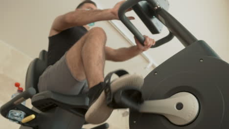 Athlete-Male-With-Face-Mask-Uses-A-Stationary-Bicycle-In-The-Gym