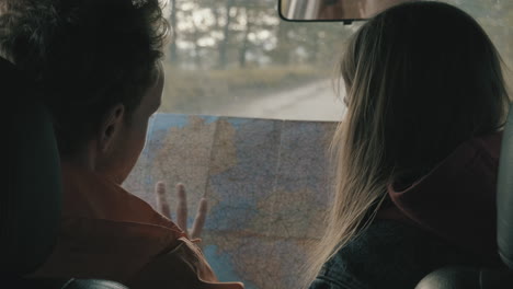 -Young-male-and-female-looking-at-a-map-inside-a-car
