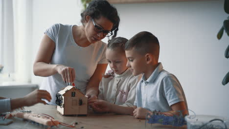 Woman-Helps-Little-Boy-And-Girl-Interested-In-Science-And-Technology-To-Build-A-Robot