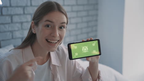 Portrait-Of-A-Pretty-Young-Woman-Showing-A-Smartphone-With-Mockup-Green-Screen